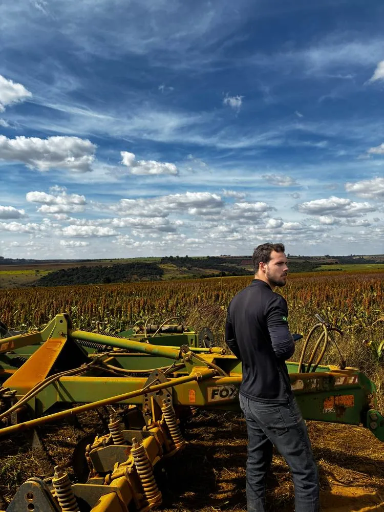 Colaborador da farm24 ao lado de implemento em lavoura de sorgo